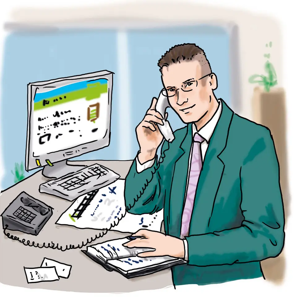 Ein Mann sitzt vor einem Computer und telefoniert.